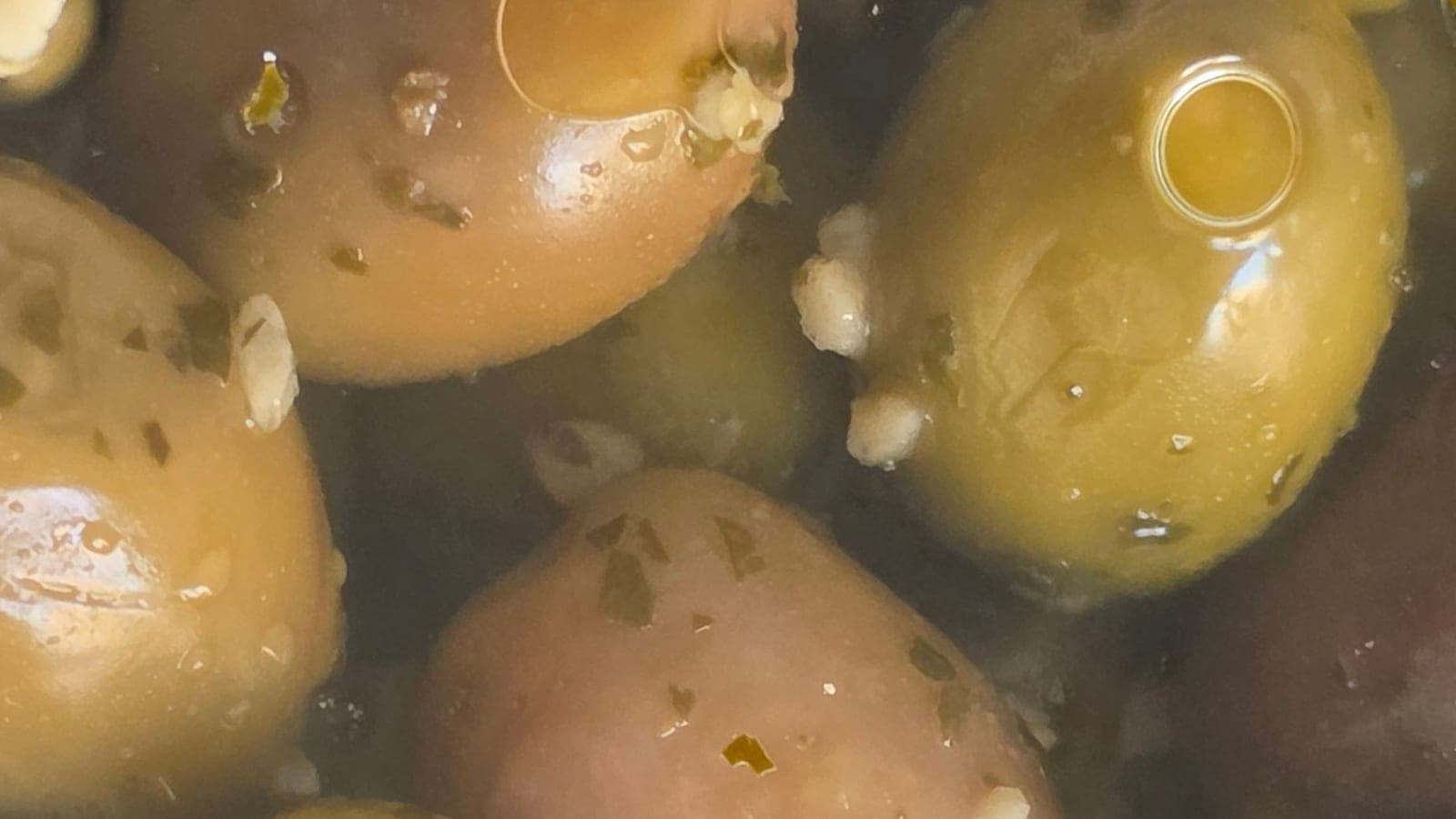 Un même bocal, deux couleurs : des olives vertes et d’autres déjà virées au rose violacé. Ni deux variétés ni deux arbres, mais le même fruit, cueilli à quelques semaines d’écart dans sa maturation. (Photo Manuel Ferreira.)