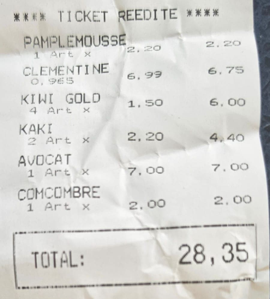 Ticket de caisse froissé d’un marchand de fruits, dont la première ligne indique PAMPLEMOUSSE, suivie de clémentine, kiwi gold, kaki, avocat et concombre